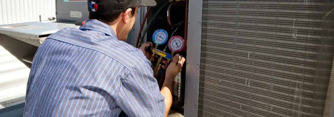 HVAC technician servicing a condenser unit in Poteau