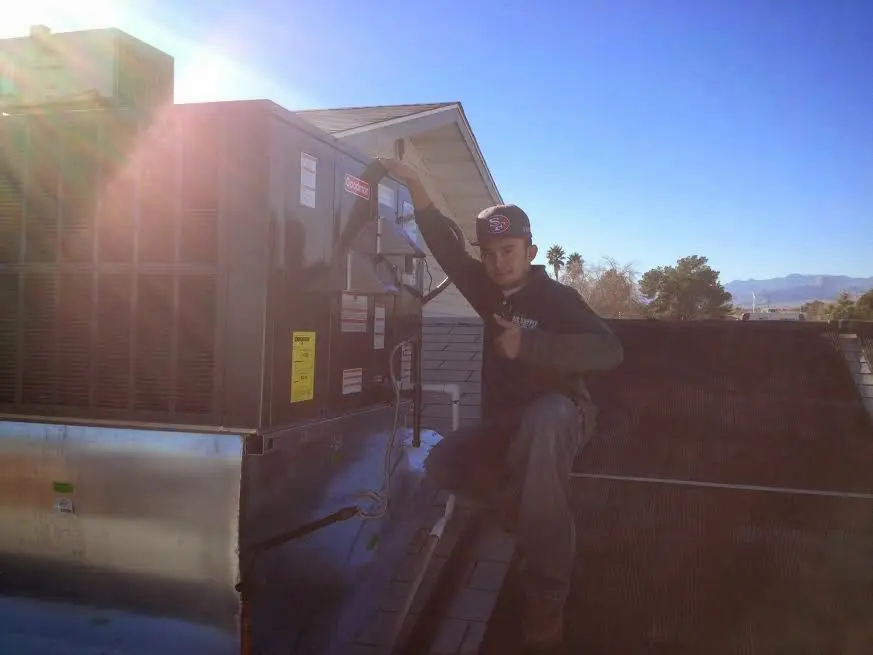 HVAC technician performing Boiler Repair on a rooftop unit in Poteau